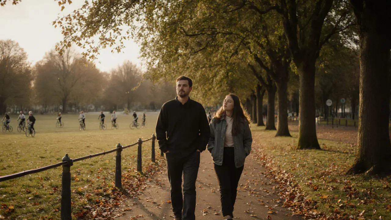 A man and woman walk side by side through Hyde Park at dusk, lost in quiet conversation among autumn trees.